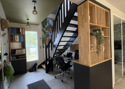 Photo après travaux d'une entrée avec escalier bois peint en noir, meuble sur-mesure bois et noir et toile décorative tropicale, réalisée par Reflets & Design architecte d'intérieur dans le Morbihan