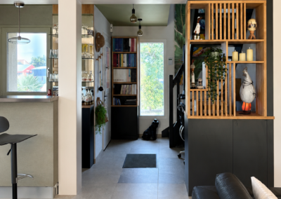 Photo après travaux d'un salon avec meuble sur-mesure bois et noir et claustra décoratif, réalisé par Reflets & Design architecte d'intérieur dans le Morbihan
