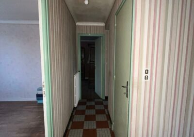 Photo avant travaux d'un couloir de maison ancienne avec papier peint rayé et carrelage damier, projet de rénovation complète à Bignan par Reflets & Design architecte d'intérieur dans le Morbihan