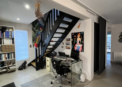 Photo avant travaux d'un espace avec escalier métallique noir et bureau sous l'escalier, projet de rénovation par Reflets & Design architecte d'intérieur dans le Morbihan